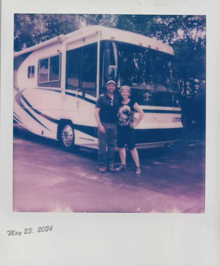 How We Quit the 9-to-5 Grind for Full-Time RV Life A couple poses in front of a motorhome. The photo is in an old polaroid format