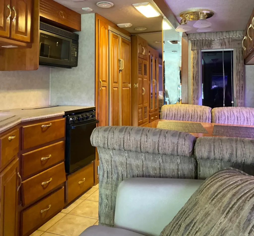A small 2000 era RV kitchen with honey pecan cabinets and brass fixtures