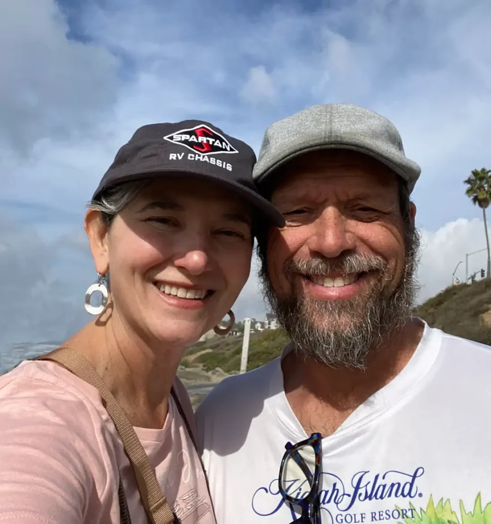 A couple smile happily in bright sunshine