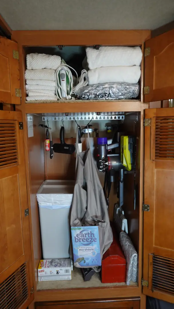 A small linen closet has been converted into a laundry, trash and cleaning space