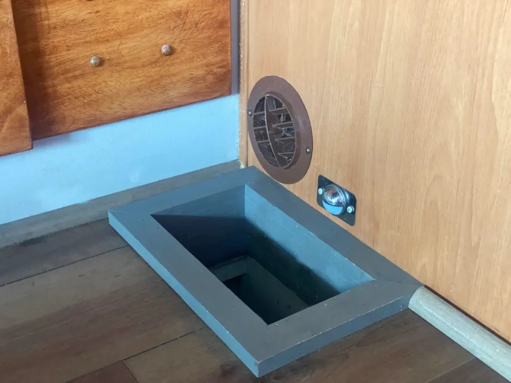 A gray framed hole in the floor reveals the interior entrance to an rv litter box bay