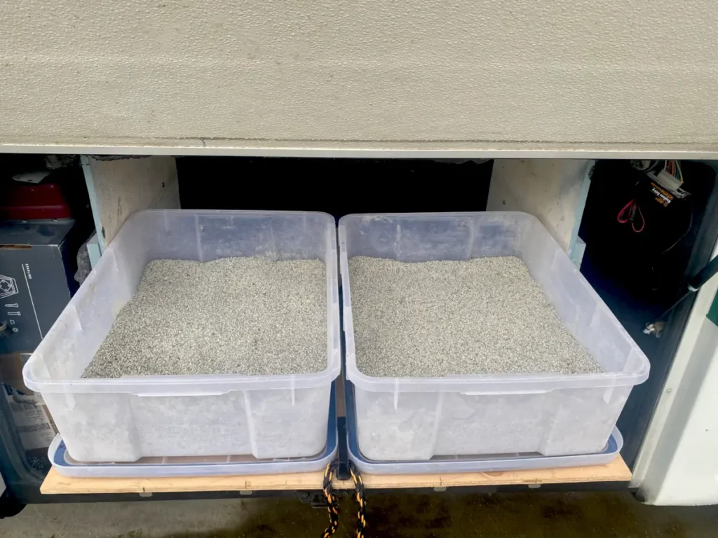 An open rv bay reveals two litter boxes sitting on a moveable tray