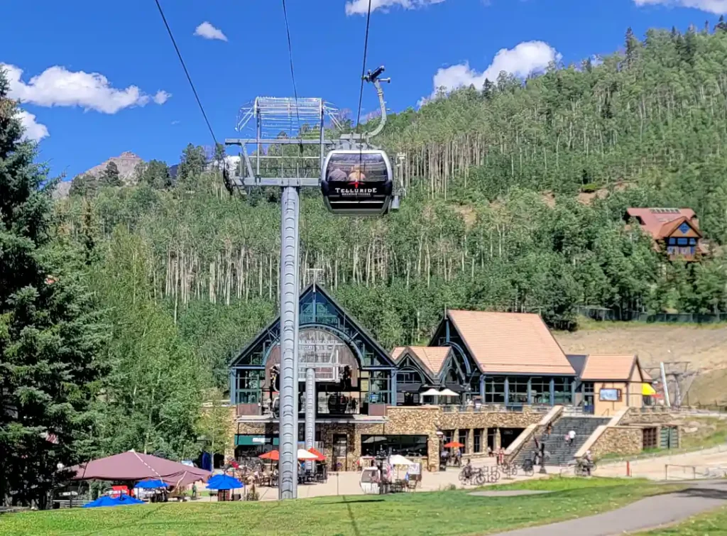 A gondola leaves its port to ascend a mountain.